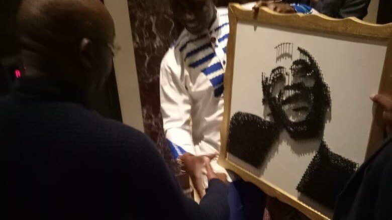 A framed portrait artwork being shown at an event.