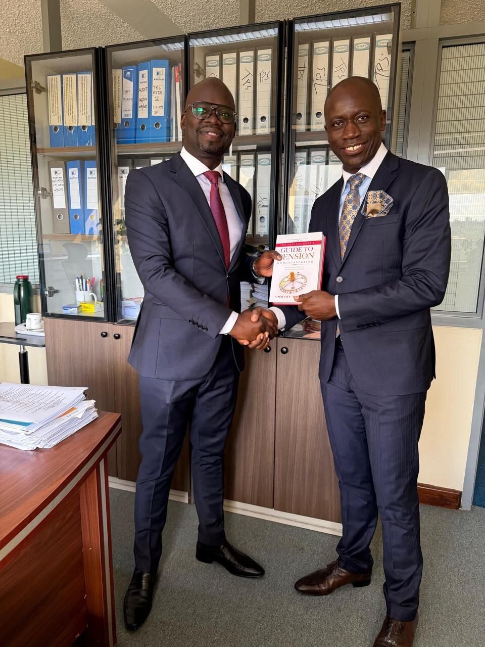 Two men in suits holding a copy of the book.